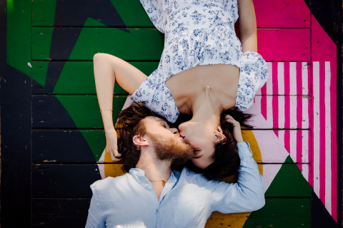 A portrait taken in Montpellier shows a couple lying on a vibrant wooden deck, with the woman upside down as they kiss, creating a yin yang symbol with their bodies.