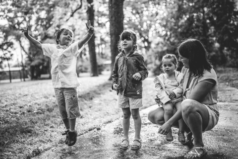 A lifestyle image created at LOIRE 42 captures a joyful family playing in the rain, with the children giggling and splashing in puddles, their faces beaming with happiness.